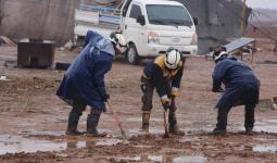 فرق الدقاع المدني خلال إصلاح طرقات مخيمات النازحين في سوريا بعد أن غمرتها مياه الأمطار