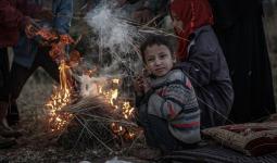 طفل سوري نازح مع عائلته يجاول كسب شيء من الدفء في ظل الجو البارد في إدلب
