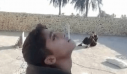 الطفل العراقي أثناء تصويب والده على هدف في فمه