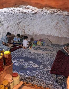 يجلس أحمد خليل مع عائلته في كهف حفره بالصخر